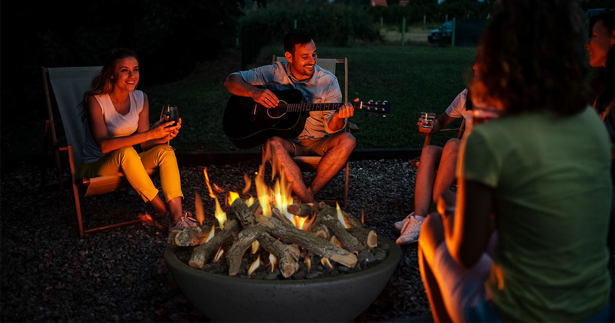 Grand Canyon outdoor fire bowl with gas logs burning at dusk while people sit around it