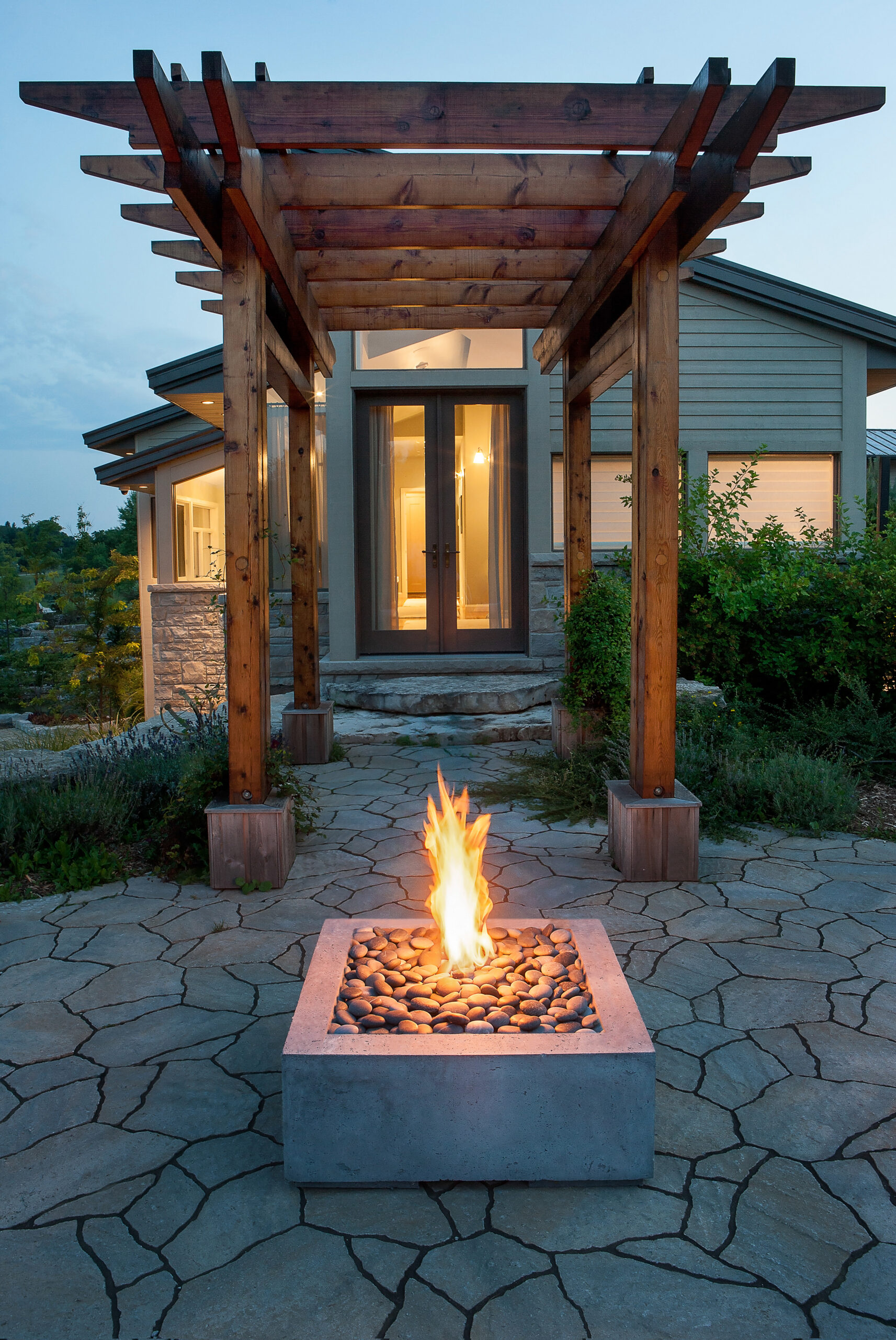 HPC concrete gas fire pit on a stone patio under a wood pergola