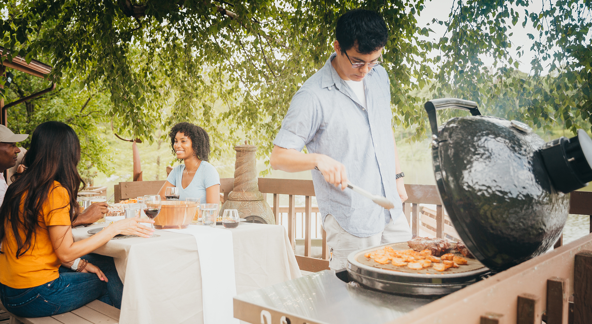 Primo oval kamado grill with the lid open on a wooden deck