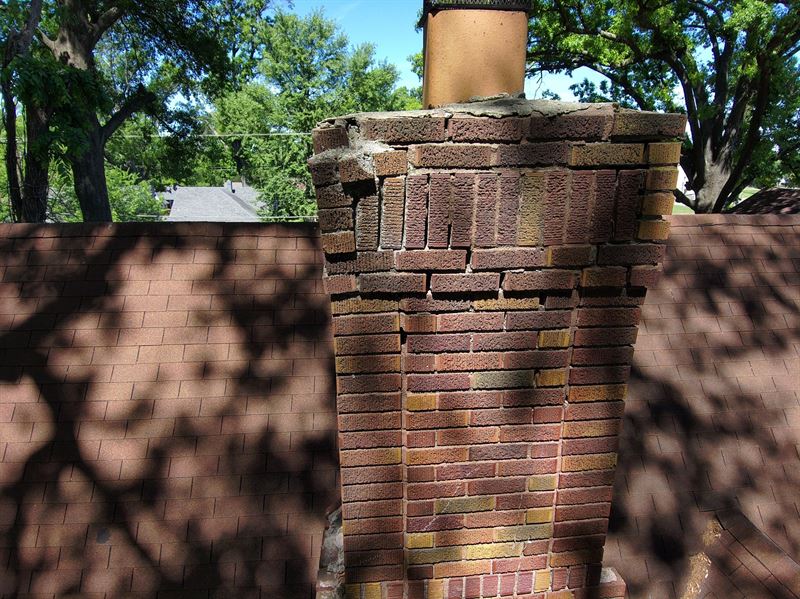 Severely deteriorated brick chimney with crumbling crown and spalling brick before Madewell rebuild