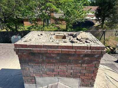 Old cracked chimney crown broken out with concrete debris on top and the clay flue tile opening exposed before a new crown is poured