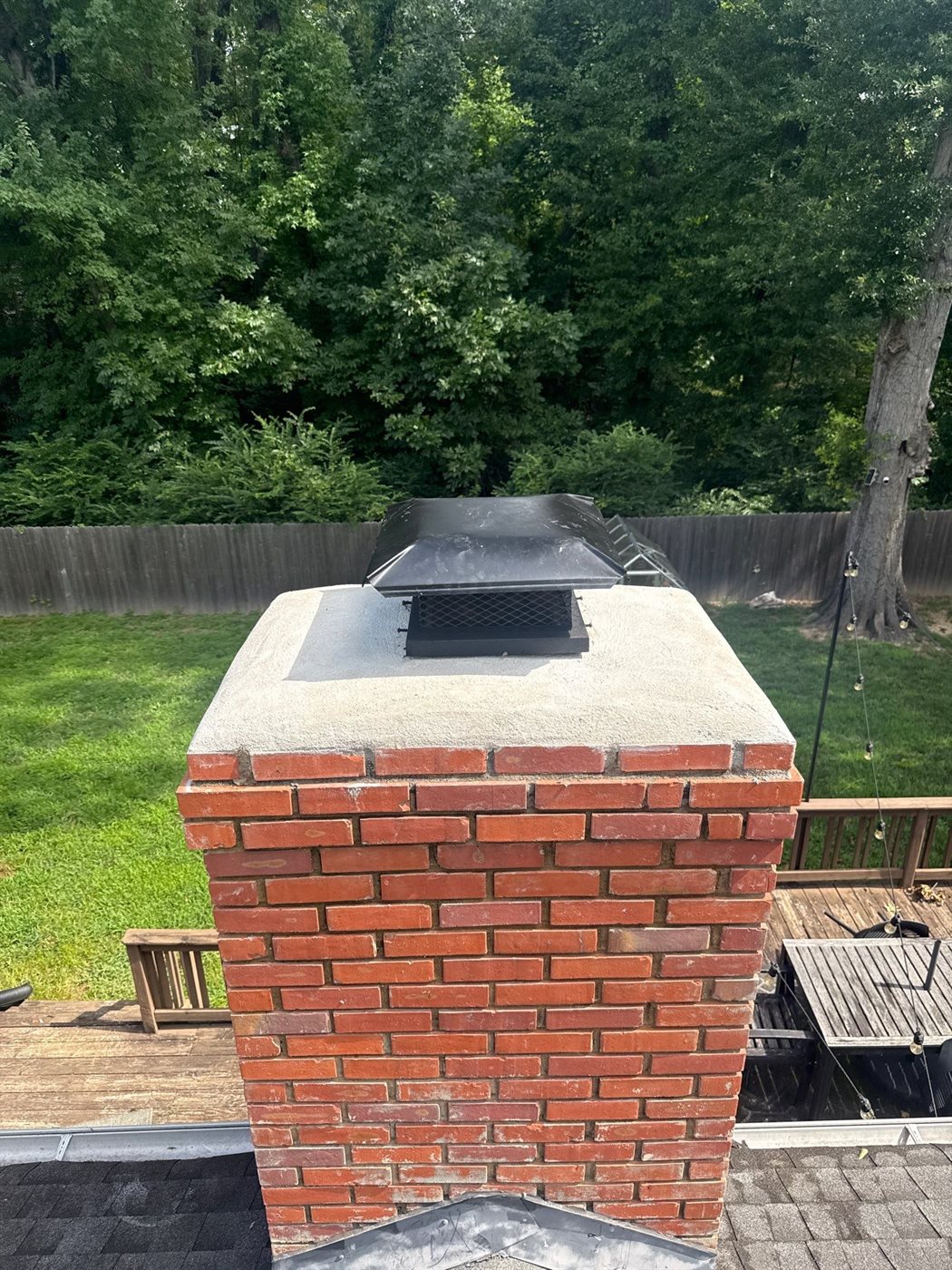 Finished brick chimney with crown and black stainless cap on a Southaven, MS home