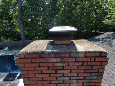 Side view of cracked dirty chimney crown and rusted cap before Madewell repair in Memphis