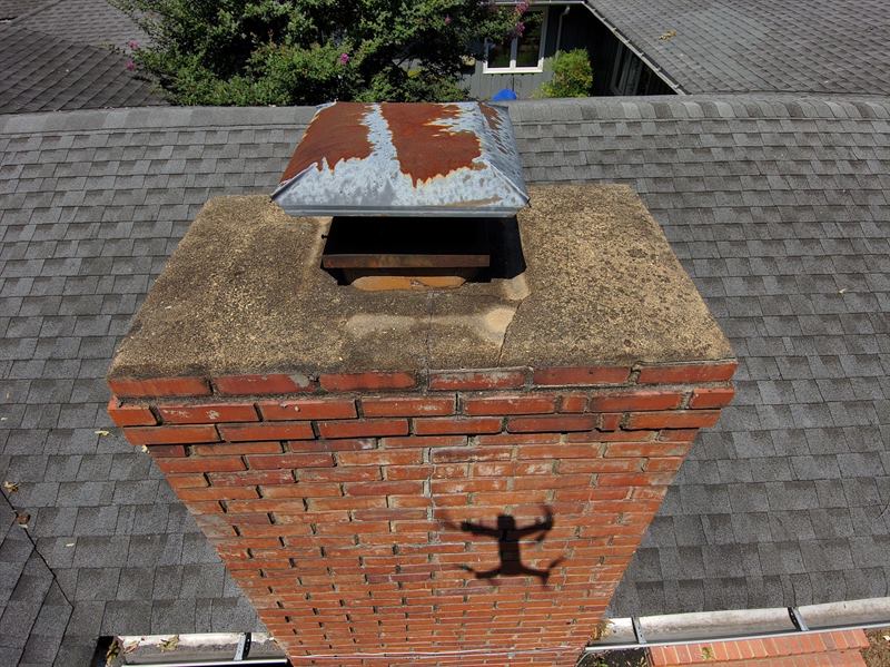 Drone view of cracked chimney crown and heavily rusted open metal cap before repair in Memphis