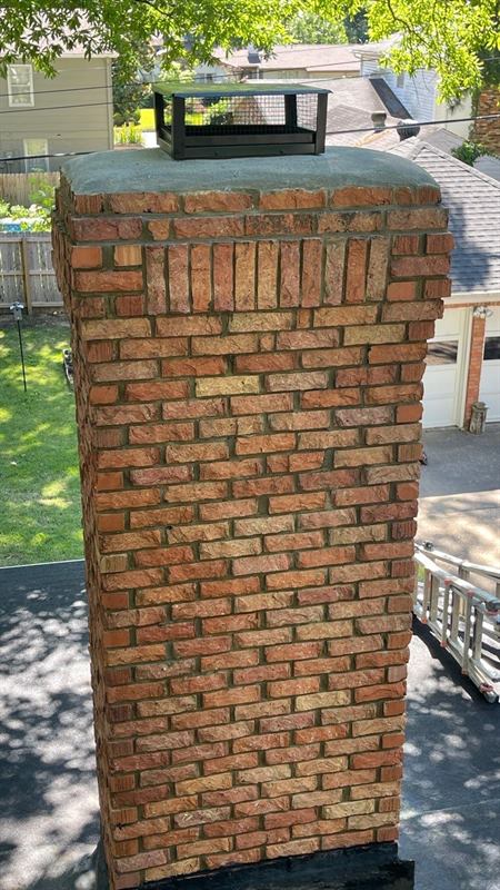 Same brick chimney rebuilt with poured concrete crown and black stainless cap after Madewell repair in Memphis