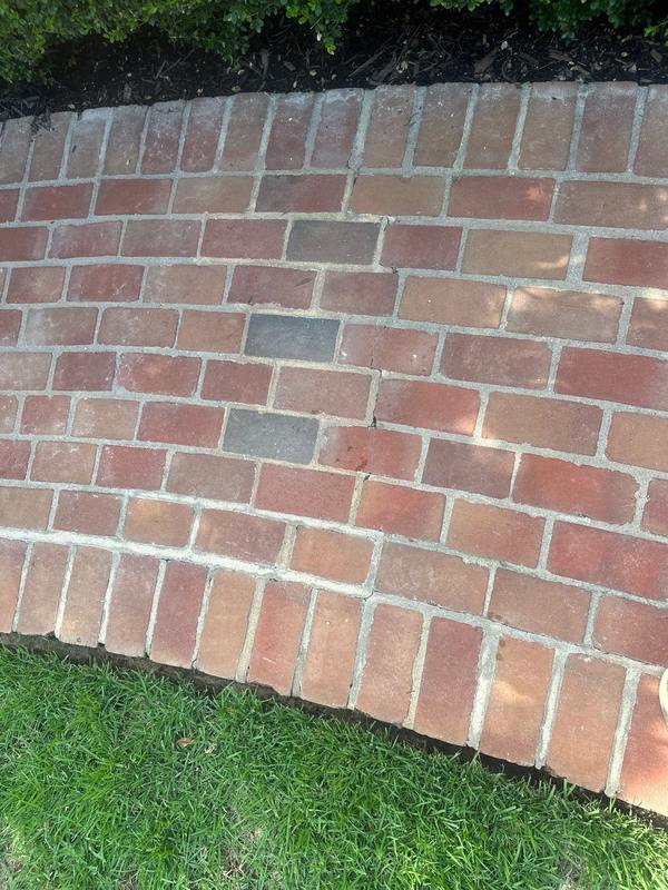 Brick flatwork with worn, washed-out mortar joints before restoration