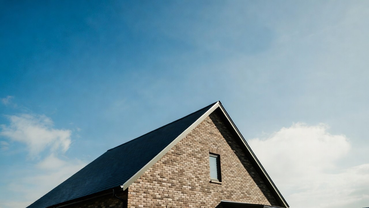 Close-up of a brick gable peak and rake line against a blue sky