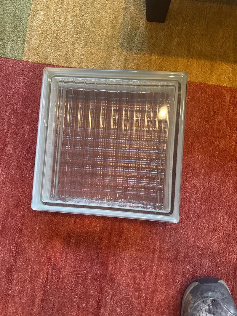 Single ribbed replacement glass block unit on the floor, matched to an existing Memphis glass-block wall