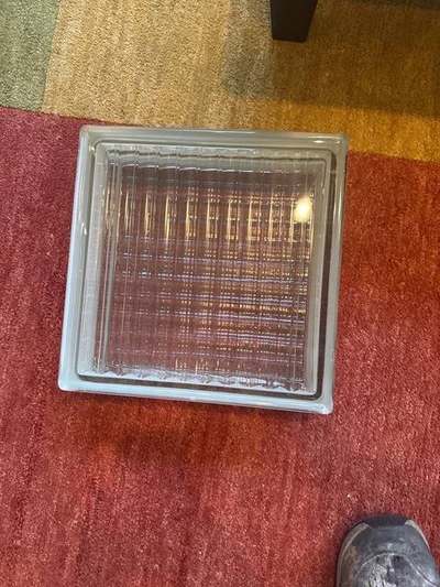 Single ribbed replacement glass block unit on the floor, matched to an existing Memphis glass-block wall