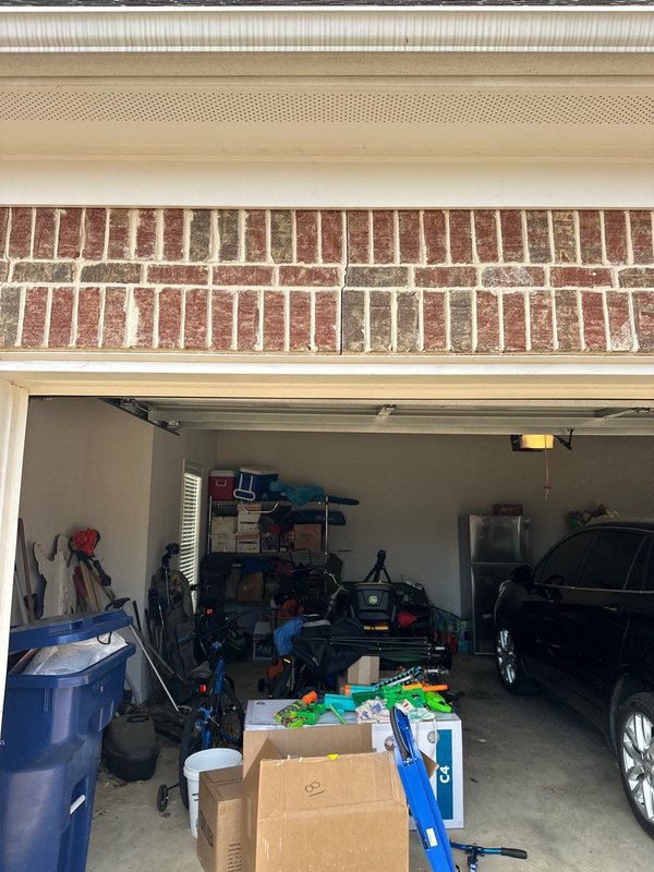 Horizontal crack running across the brick soldier course directly above an open garage door