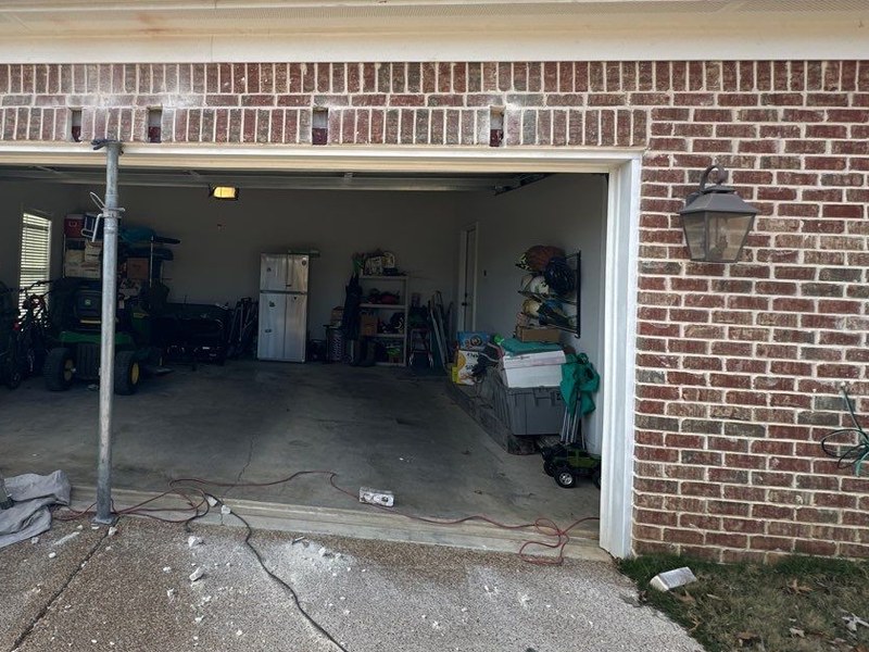Steel shoring post supporting a garage door opening during lintel repair with the brick course above opened up