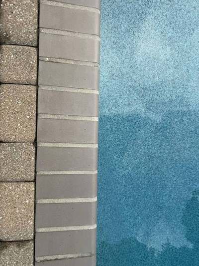 Brick pool coping with fresh mortar joints running between the paver deck on one side and the pool water on the other
