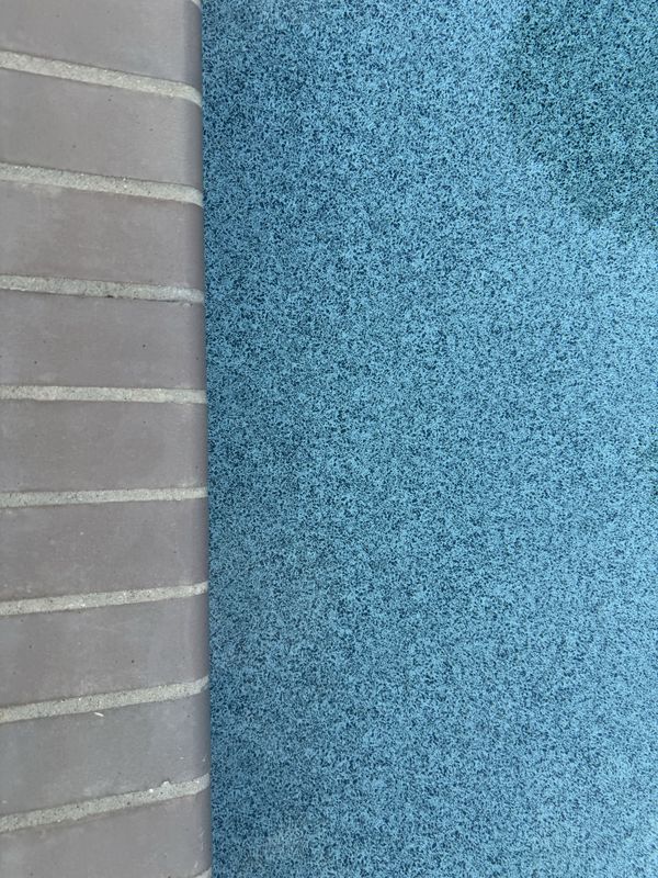 Close view of brick pool coping with fresh mortar joints packed full and struck flush, beside the blue water of the pool