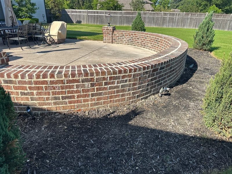 Curved brick patio retaining wall with fresh color-matched tuckpointing by Madewell Masonry in Memphis