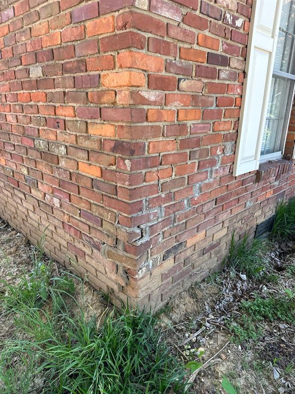 Stair-step cracked brick foundation corner with failed mortar joints — condition example