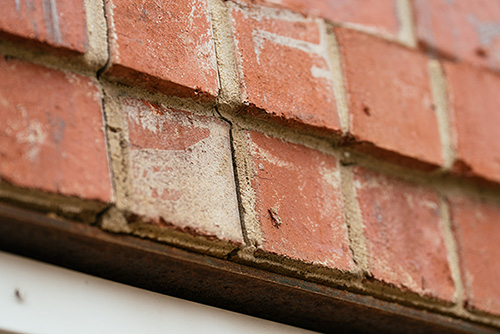 Cracked masonry above garage door close up 