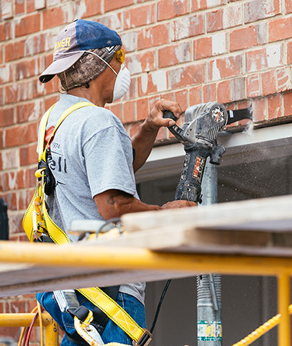 Man with backwards hat wearing mask using masonry tool to fix lintel line on gargageFixing a sagging lintel 