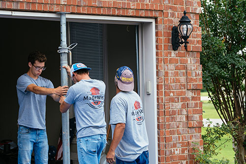 Three Men adding support beam to garage door for lintel repairs - Madewell Masonry