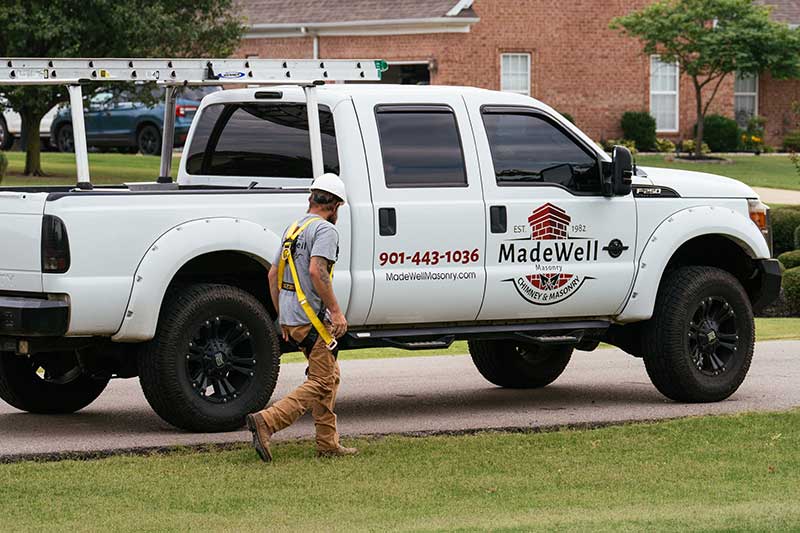 Man with harness on walking next to white pickup truck