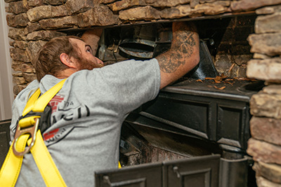 Tech inspecting above fireplace inside chimney - Madewell Masonry