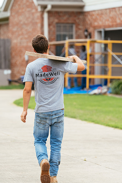 Technician carrying wood plank over his shoulder