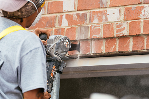 Technician cutting into brick mortar