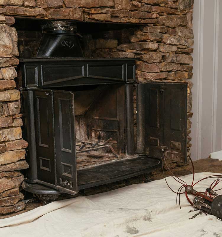 Old Black Wood Fireplace with exposed inside firebox with tools in front 