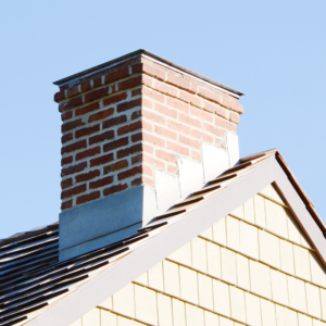 a masonry chimney with flashing and a blue sky in the background