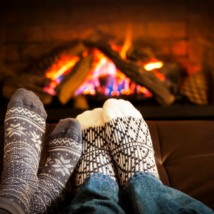 two sets of feet with cozy socks in front of a burning fireplace